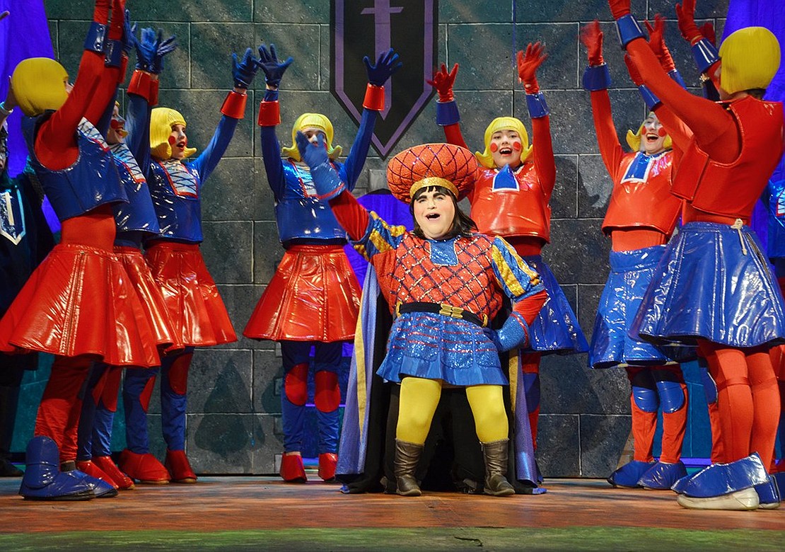 In “What’s Up, Duloc?” Lord Farquaad (played by Lee Price) sings about the “improvements” he’s making to the castle with the help of the Duloc dancers.     