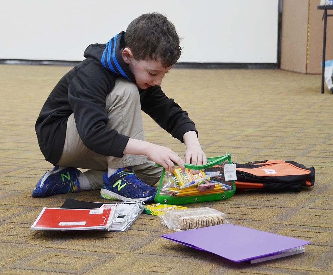 Hayden Goldstein, a 6-year-old Rye Brook resident, excitedly stuffs a backpack with folders, notebooks, markers and snacks to donate to a child in foster care. The 62 backpacks were donated by Future Stars.