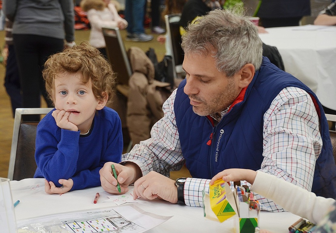 Fito Waisburg and his 4-year-old son Alan, Rye Brook residents, color Star of David emblems to decorate a KTI banner celebrating the synagogue’s 130th anniversary. 