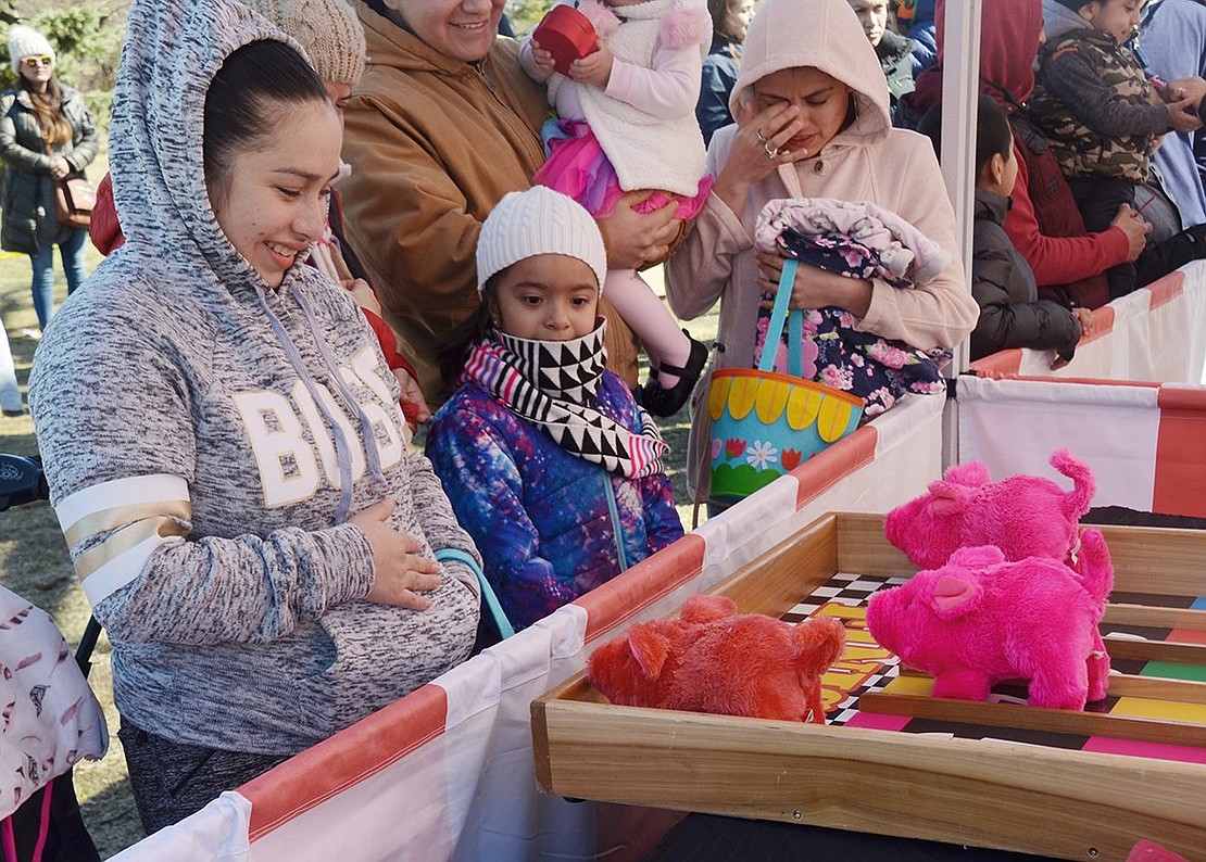 Bundled up Port Chester 6-year-old Andrea Cega watches Port Chester resident Rubia Maricla Alvarado smile as her red pig wins the race. 