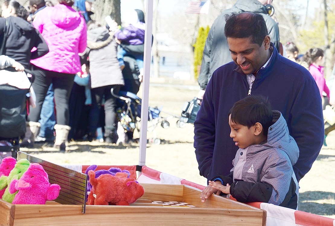 With an intense stare, William Street resident Christopher Varghese, a 6-year-old Park Avenue School student, closely watches the piggy racing carnival game to see if his or his father Sunil’s pig will come out victorious. 