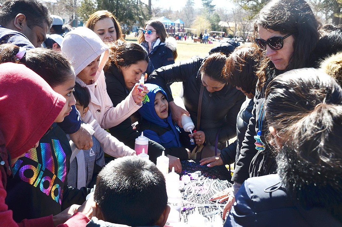 More than a dozen Easter in the Park goers gather around a table to make spirited arts and crafts to bring home. 