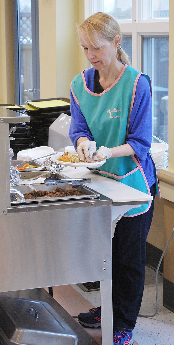 Alice Jensen of Louis Court prepares brisket and veggies dinner plates for the 40 attendees during the Seder’s meal break.