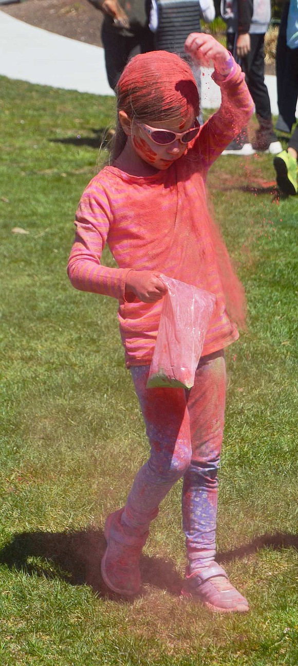 Rock Ridge Drive resident Sage Miller, 5, realizes she’s really not red enough, so she sprinkles some more red powder on top of her head. 