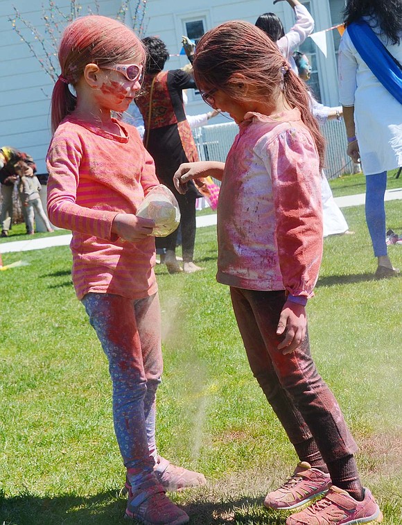 Already completely doused in red powder, 5-year-old Rock Ridge Drive resident Sage Miller (left) and 4-year-old Rockinghorse Trail resident Reia Bhuva change things up a bit and dig into a bag of green coloring.