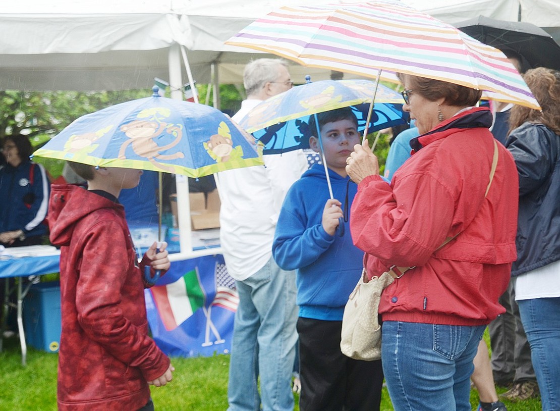 Attempting to stay dry, Blind Brook fourth-grade twins Jacob (left) and Ben Goldowsky huddle under their monkey umbrellas with their grandma Jackie, a Port Chester resident. 