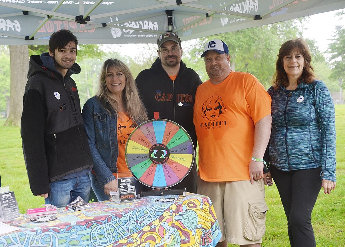 Brian Kerr (left), Susan Migliore, Jerry Fecteau, Dave Engleman and Mary Ann Gospodinov stay dry under The Capitol Theatre tent, where PC150FEST goers could spin a wheel for free stickers, magnets and concert tickets.    