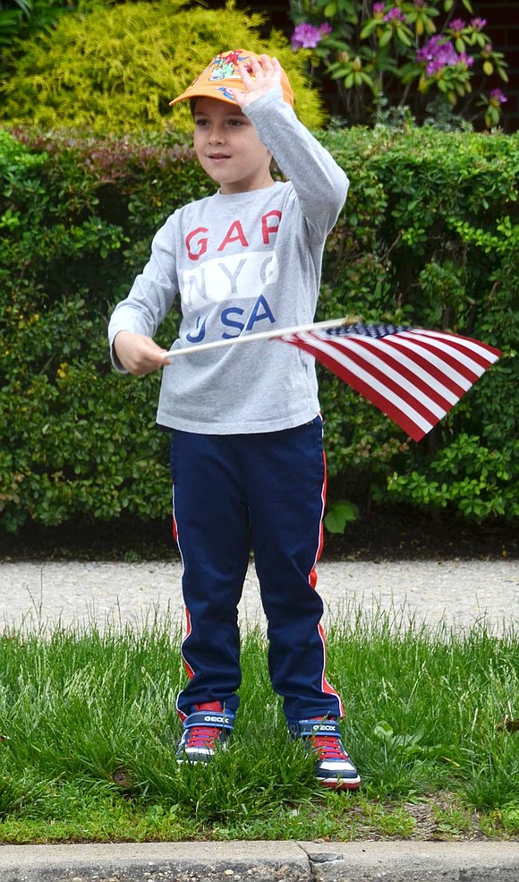 Standing toward the top of Westchester Avenue, Natan Meiri, 6½, of Rye Brook, waves as the parade passes by.