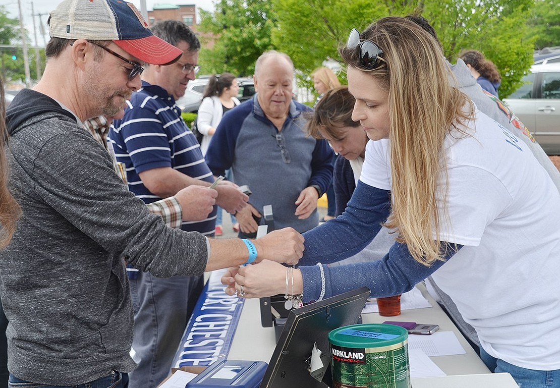 While working the ticket booth in the Marina Parking Lot on Abendroth Avenue, Rye Brook resident Michelle Rivera helps Carmine Dechiara, a longtime Port Chester resident who recently moved to Fort Lauderdale, Fla., fasten his Taste of Port Chester wristband. 