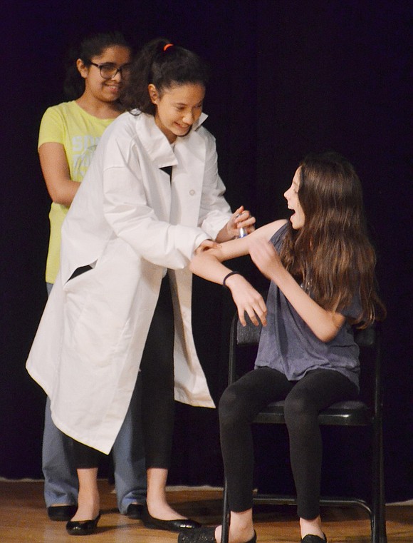 Playing an unqualified doctor in the student-created original play “Job Hunt,” sixth-grader Bridget Zelin stabs unsuspecting patient Emily Davis in the arm with a shot. Students in the Blind Brook Middle School Drama Club presented “From the Page to the Stage” to showcase original plays in the Blind Brook Middle/High School auditorium during Creaticon on Thursday, May 31. 