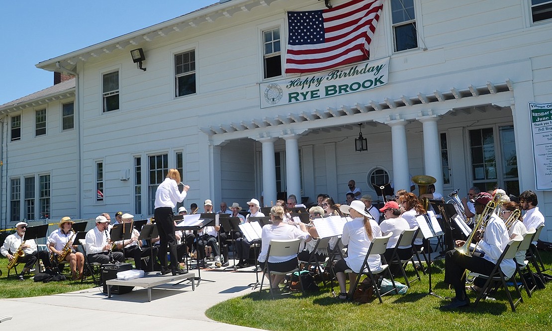 Port Chester resident Carolee Brakewood conducts the Rye Town Community Band in front of Crawford Mansion. 