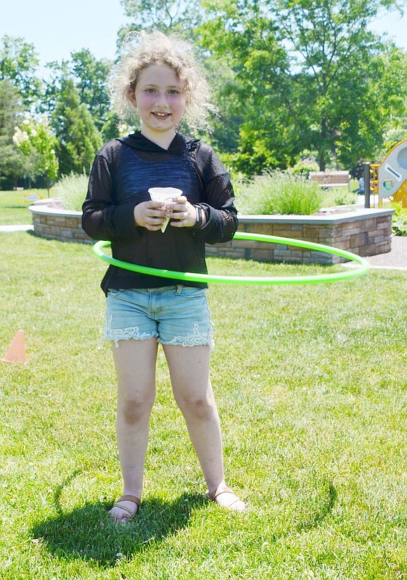 Victoria Axelrod shows off her hula-hooping skills while she finishes her snow cone. For several minutes, the Ridge Street Elementary School second grader never dropped the hoop. 