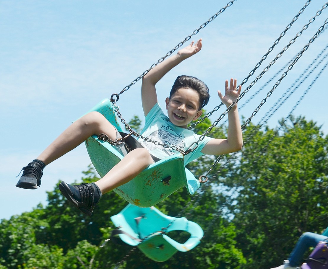 Whee! John F. Kennedy Elementary School third-grader Evan Tay feels the wind between his fingers as he spins around on the swing ride. 
