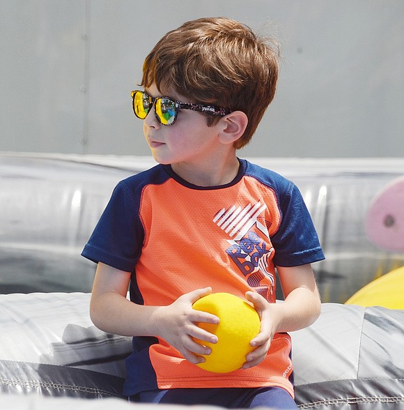 Hunter Drive resident Anthony Gebriael, 5, looks cool in his sunglasses as he casually hangs out with his newfound ball in the life-sized Hungry Hungry Hippos inflatable setup.