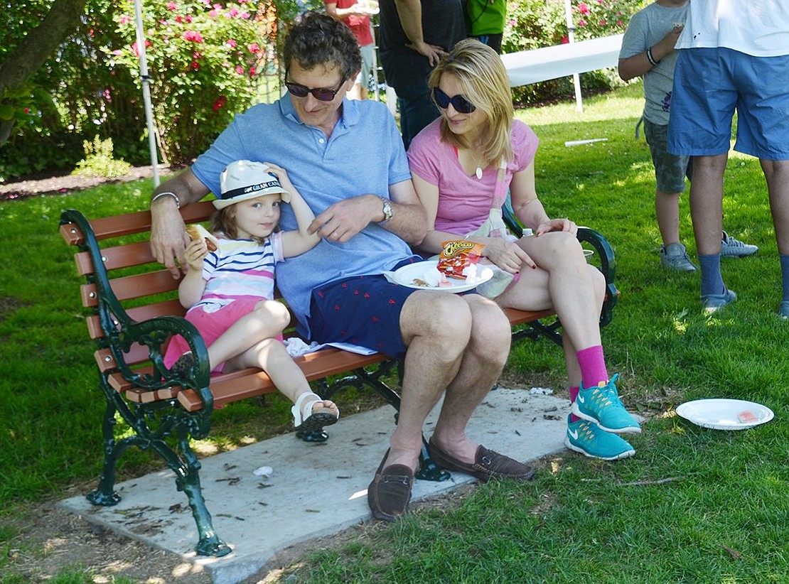 Some of Rye Brook’s newest residents from England, Svetlana and Richard Luca-Phillips and their 3-year-old daughter Aeliana, beat the heat by enjoying their snacks on a bench in the shade. 
