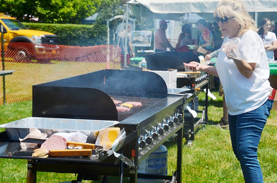 Rye Brook resident Pat Cappelletti grills up several hamburger patties for hungry birthday party attendees. Cappelletti is volunteering with Westchester Bank, one of the sponsors of the celebration. 