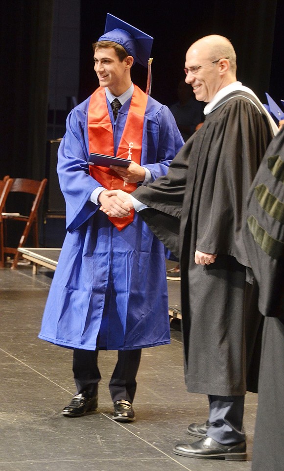 Board of Education President Jeffrey Diamond shakes Jonathan Egol’s hand while awarding his diploma.