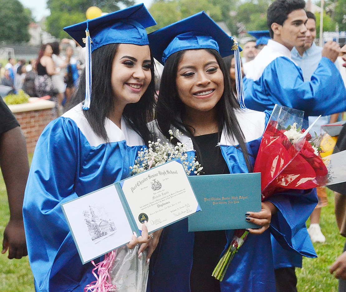 With loads of flowers and smiles, Michelle Zapata (left) and Diana Naula show off their freshly received diplomas. 