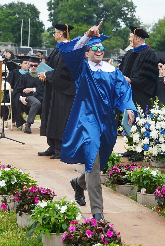 Michael Boccarossa points to loved ones in the audience as he proudly struts down the aisle after receiving his diploma.