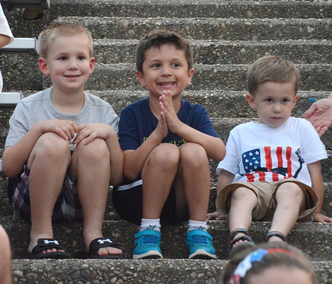 Six-year-olds Aidan Brenzel (left) and Luke Doherty join 3-year-old Zach Brenzel on the steps at Ryan Stadium watching the program before the fireworks. The six-year-old Port Chester residents both received trophies for their entries in the Fourth of July student contest on the history of Port Chester.