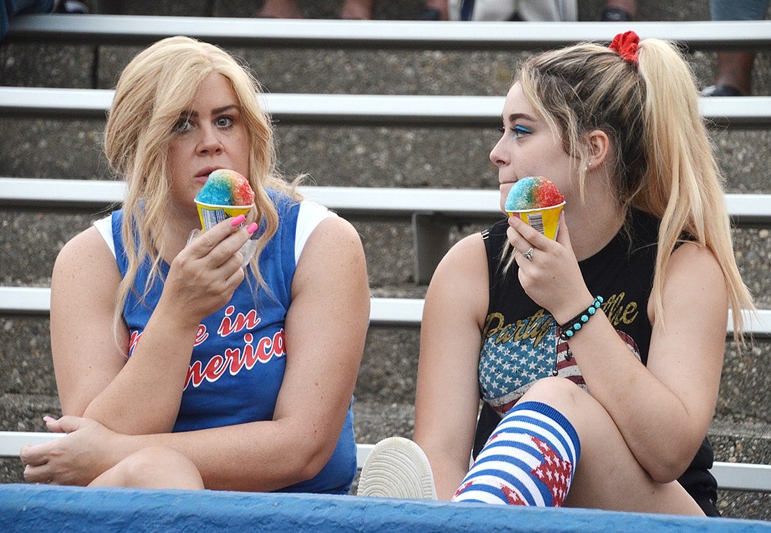Mother and daughter Lauren and Debbie Vellecca of Rye Brook eat multi-colored snow cones in the stands.