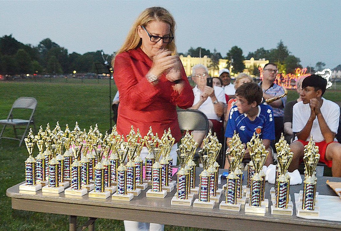 Hope Klein of Rye Brook, who organized the Independence Day celebration for the sixth year, looks over the trophies to be given out to students who participated in the contest which asked them to draw or write about the history of Port Chester.