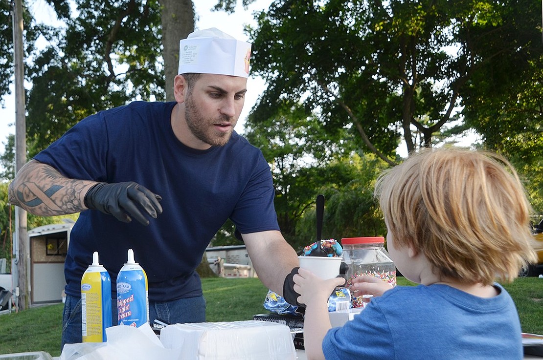 Rye Brook Parks Department employee Waz Colantuono spends the evening serving residents sweet treats, as he takes on the role of ice cream scooper and topper.