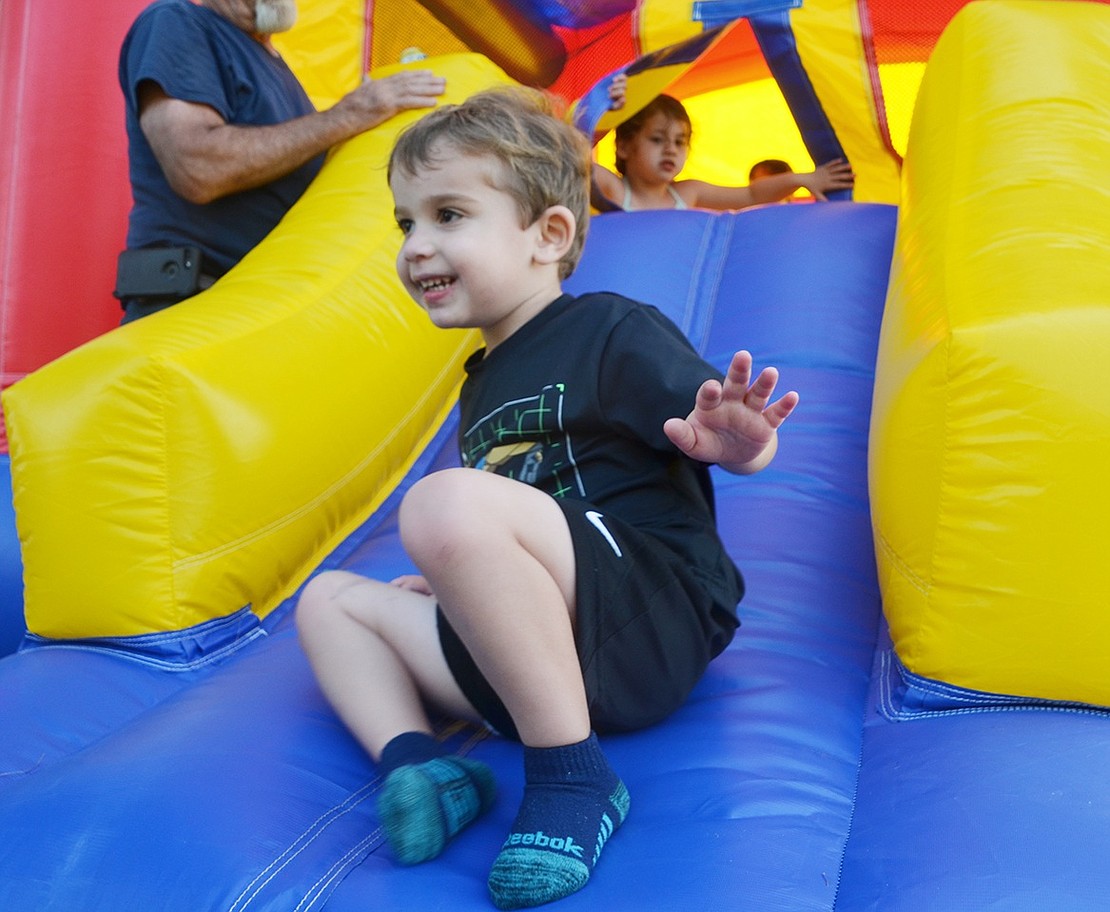 Sliding out with a smile, 3-year-old Carlton Lane resident Cooper Okun exits the bounce house after spending time jumping inside.