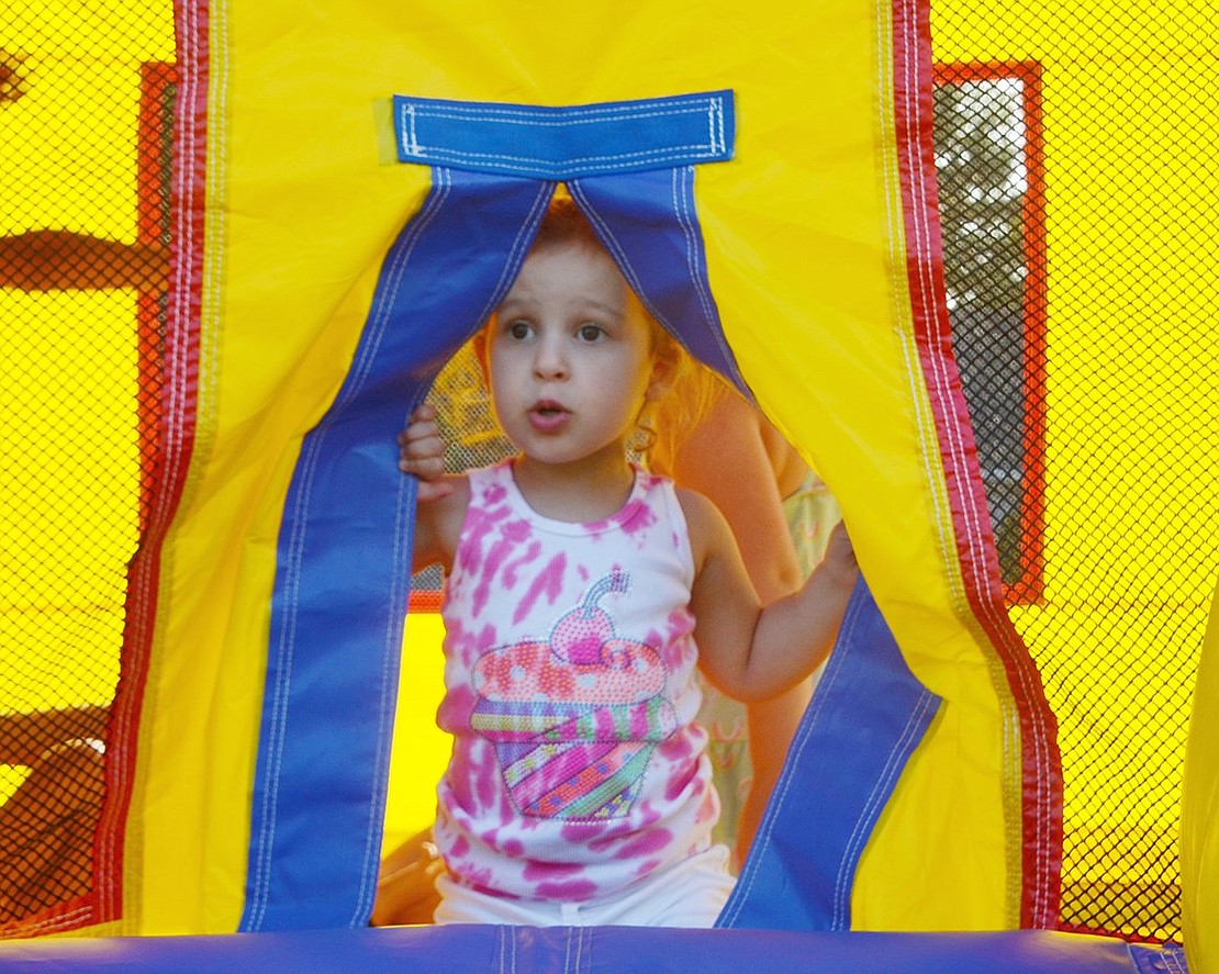 Peek-a-boo! Boxwood Place resident Emma Wiener, 2, pokes her head through the opening of the bounce house. 