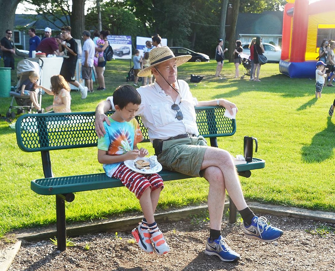 Philip Russell (right) and Kuan Russell-Tang, of Rock Ridge Drive, enjoy the nice summer evening together on a bench at the Pine Ridge Park playground.