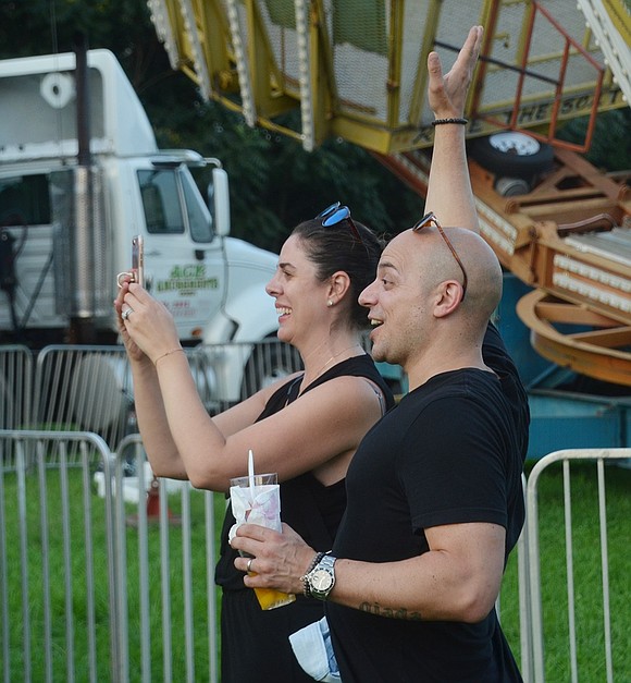 While their twin daughters spin on the swing ride, Port Chester residents Daniela and Felix Rubino wave and snap pictures. 