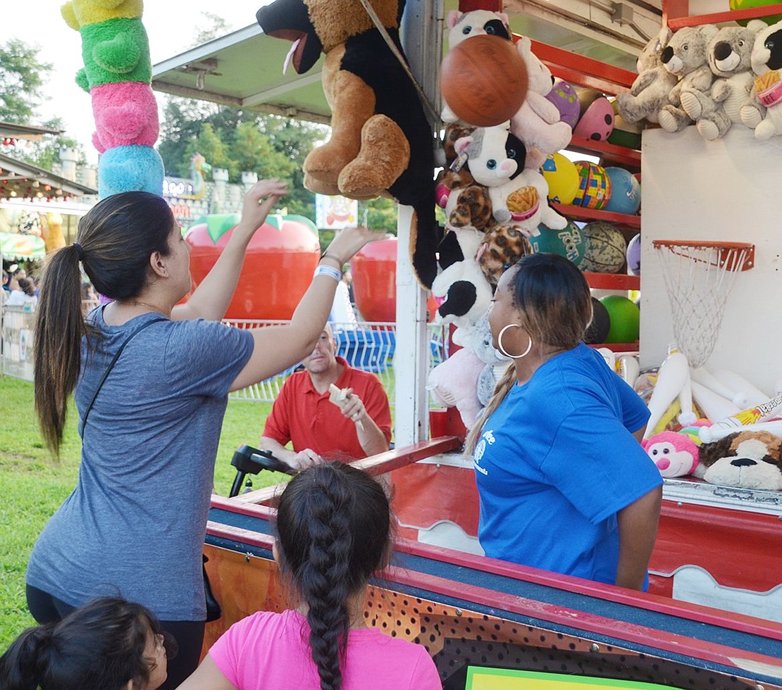 Impressing her family, Alexandra Garcia shows off her hoop skills at one of the many game vendors at the carnival. The Washington Street resident won a white inflatable bat for her efforts. 