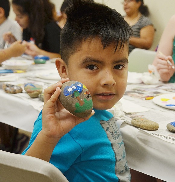 After drawing a tree in a field, the sky and a dog, John F. Kennedy Elementary School soon-to-be first-grader Alexis Lopez shows off his elaborate rock during a community rock painting event in the Port Chester-Rye Brook Public Library community room on Wednesday, Aug. 22.