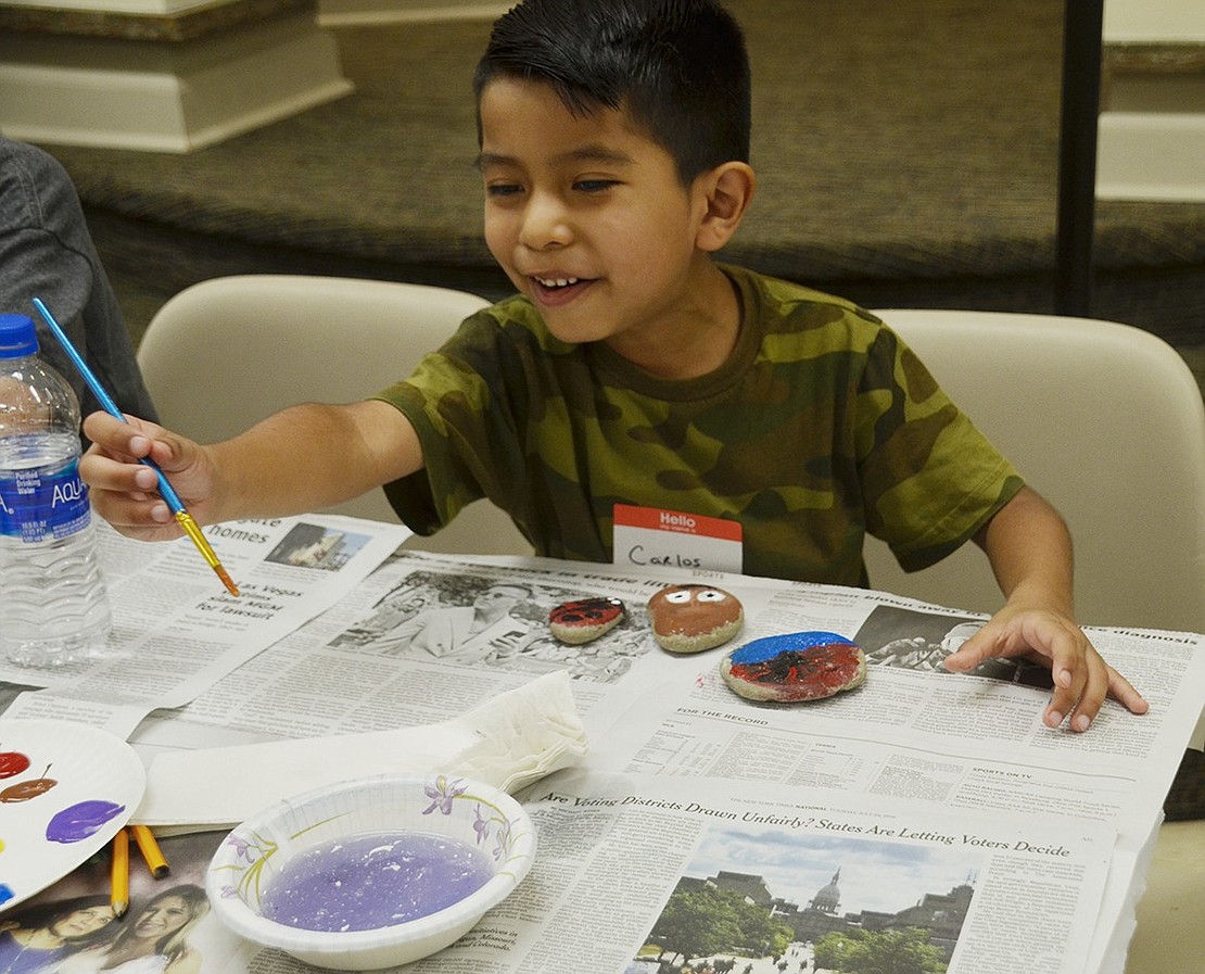 Six-year-old John F. Kennedy student Carlos Rojas is thrilled to see how washing his paint brush turns the water purple. 
