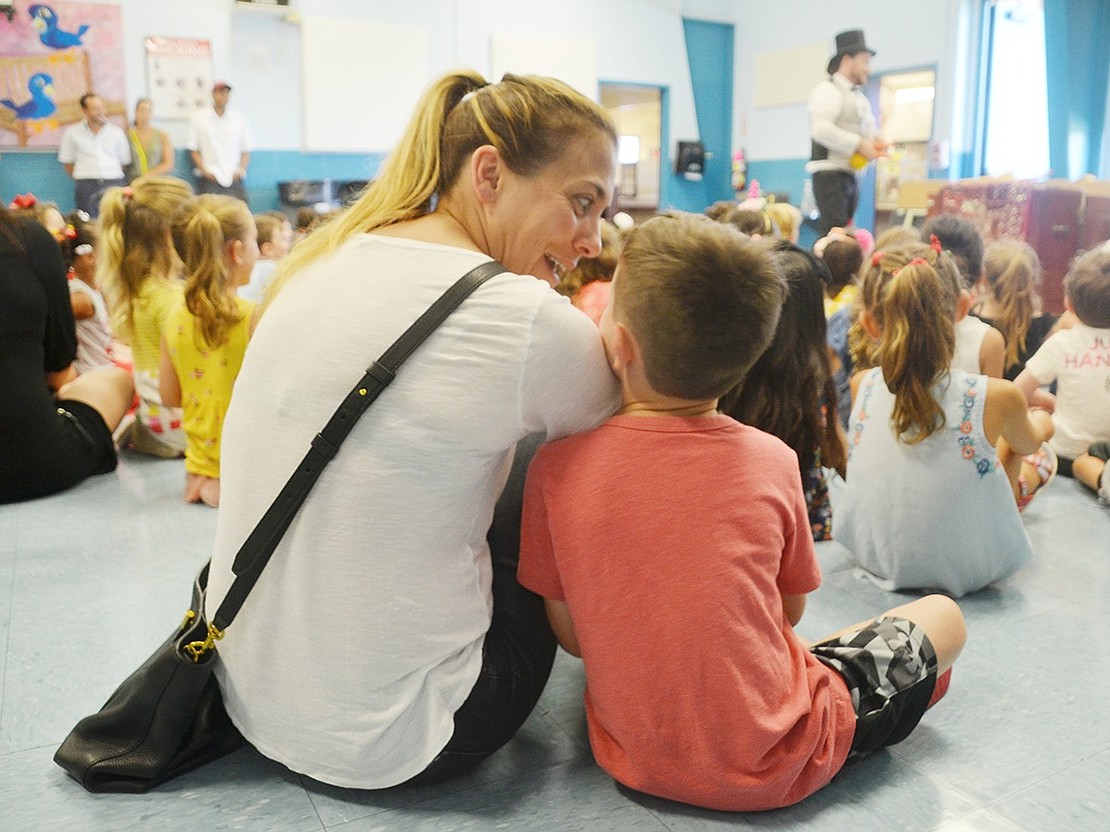 Getting cozy in the back row, Aviva Stein comforts her son, Jake, with silly faces during the magic show at the social intended to introduce incoming kindergarteners and their families before school starts on Tuesday, Sept. 4.