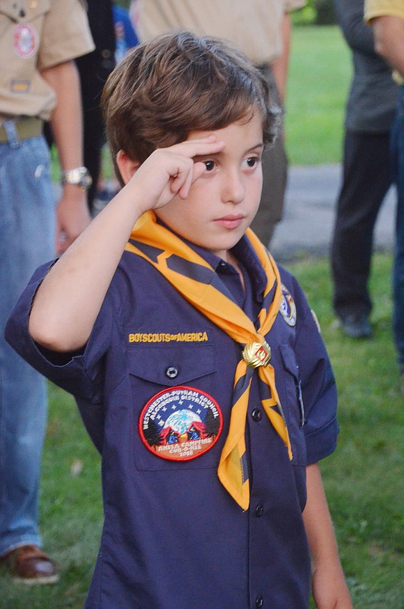 As Anastasia Marcos sings the National Anthem, Cub Scout Pack 3 member and Ridge Street Elementary School second-grader Matthew Geller shows respect with a salute.