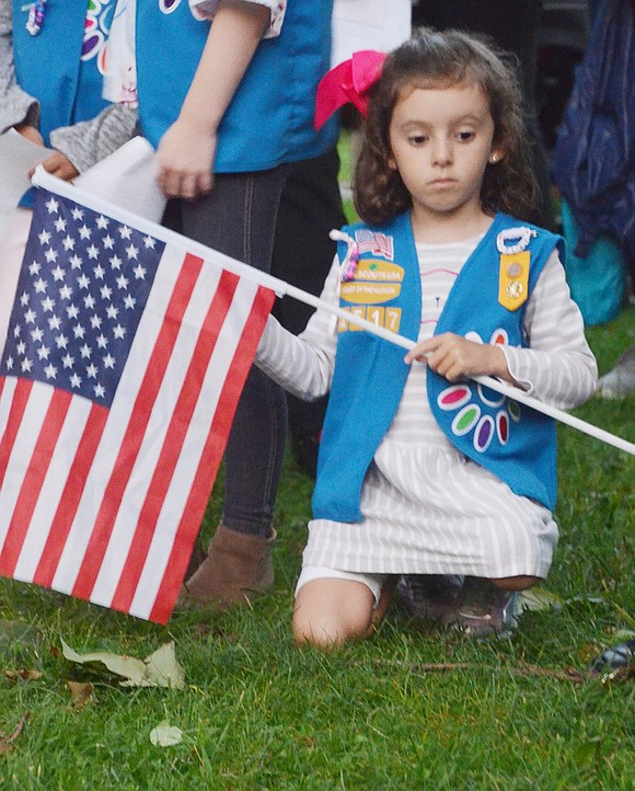 While clutching her American flag, King Street School first-grader and Daisy Girl Scout Troop 02517 member Violet Van der Wateren contemplates as speakers discuss the impact of the 9/11 tragedies.