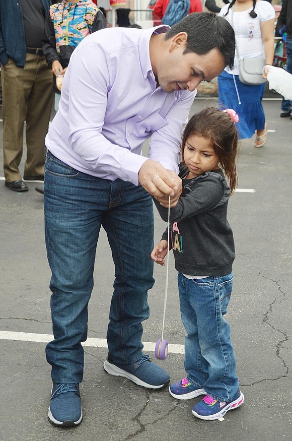 José Jain Morales, a Port Chester resident who originates from Colombia, teaches his slightly frustrated 4-year-old daughter Jhoselyn Michelle Morales how to use the purple yo-yo she just made at the Home Depot arts and crafts table.