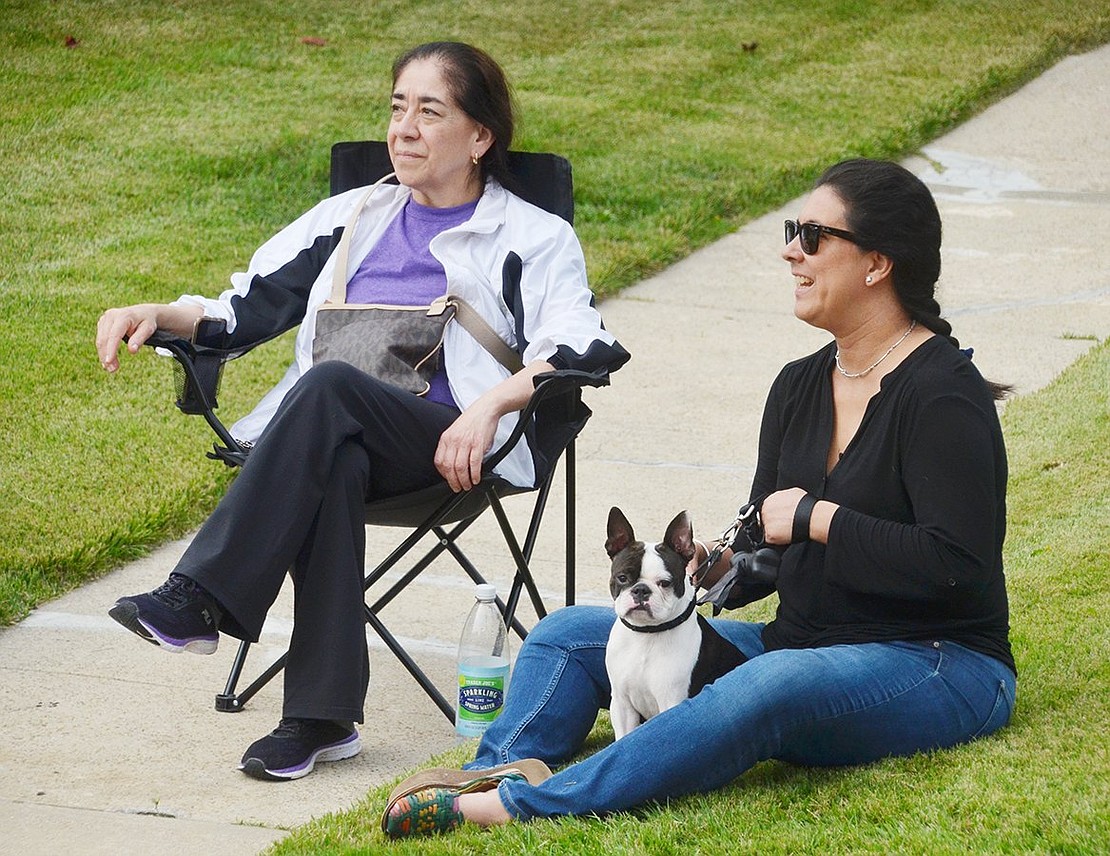 Angelica Barajas (right) and her aunt, Marta Sanchez, watch the parade outside their Westchester Avenue home with their dog, Jack the Boston Terrier.