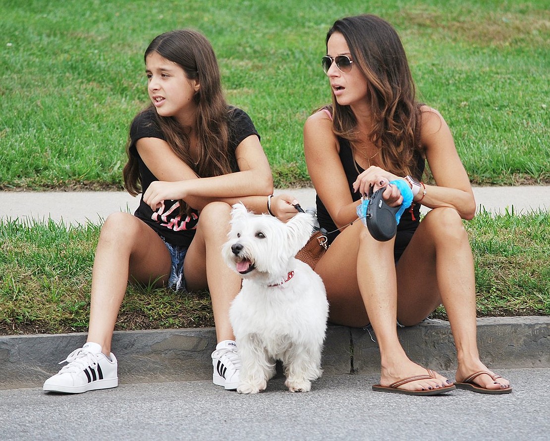 Rye Brook residents Isabella, 10, and her mother Antoniette Montesano find good seats on a Westchester Avenue curb so they can watch the procession with their Westie Bailey.