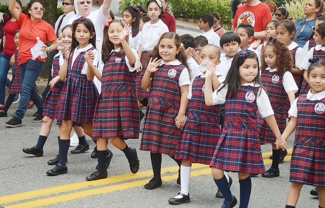 A group of girls from Corpus Christi-Holy Rosary School holds hands while they wave to the spectating crowds.