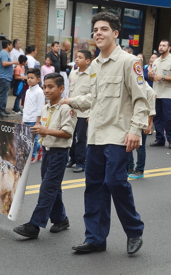 Michael Quintana, 17, tenderly places his hand on 8-year-old Elian Velasquez’s shoulder. The Port Chester residents are singing along to soulful Christian music as they march with the Second Pentecostal Church.