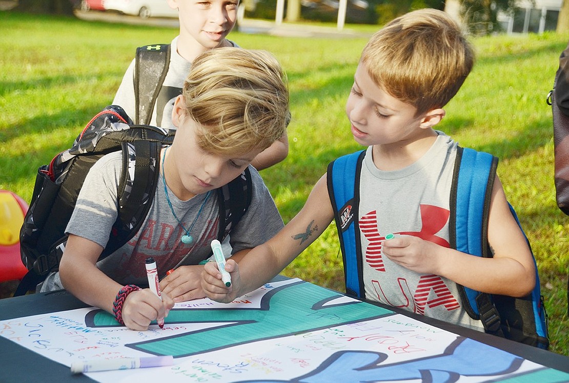 Second-grade buddies Sebastian Candee (left) and Zach Capon pick out the perfect spot to sign their names together.