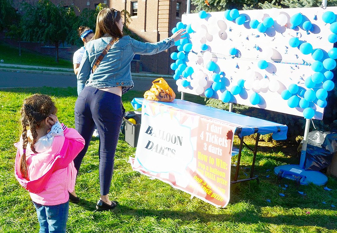 As her 5-year-old daughter Luna covers her ears to prepare for the pop, high school English as a Second Language teacher and Hawthorne resident Kathryn Zappone throws darts at a board of balloons.