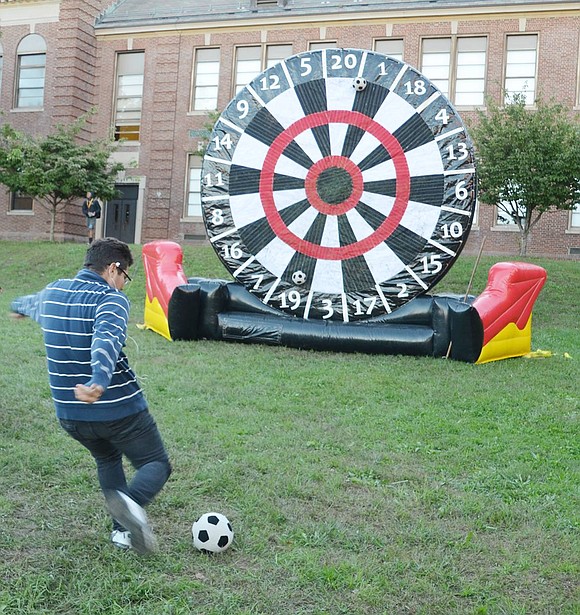 High School sophomore Erick Umanzor gets a running start to kick the soccer ball at the giant blowup dart board.