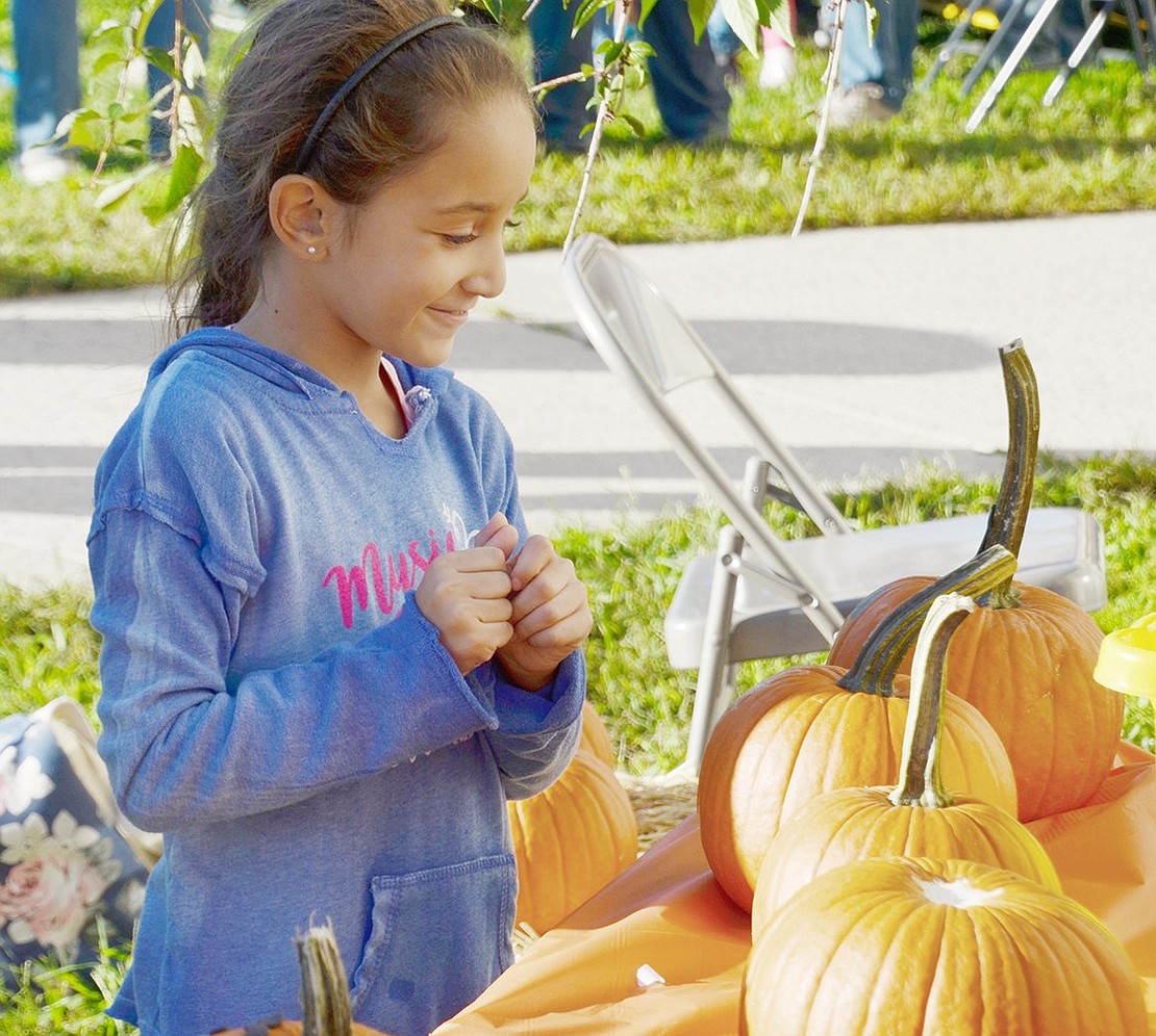 Clearly satisfied with her art, King Street Elementary School second-grader Alexis Patafio gleefully smiles at her pumpkin during the PTO-sponsored Harvest on Park festival at Park Avenue Elementary School on Friday, Oct. 12.