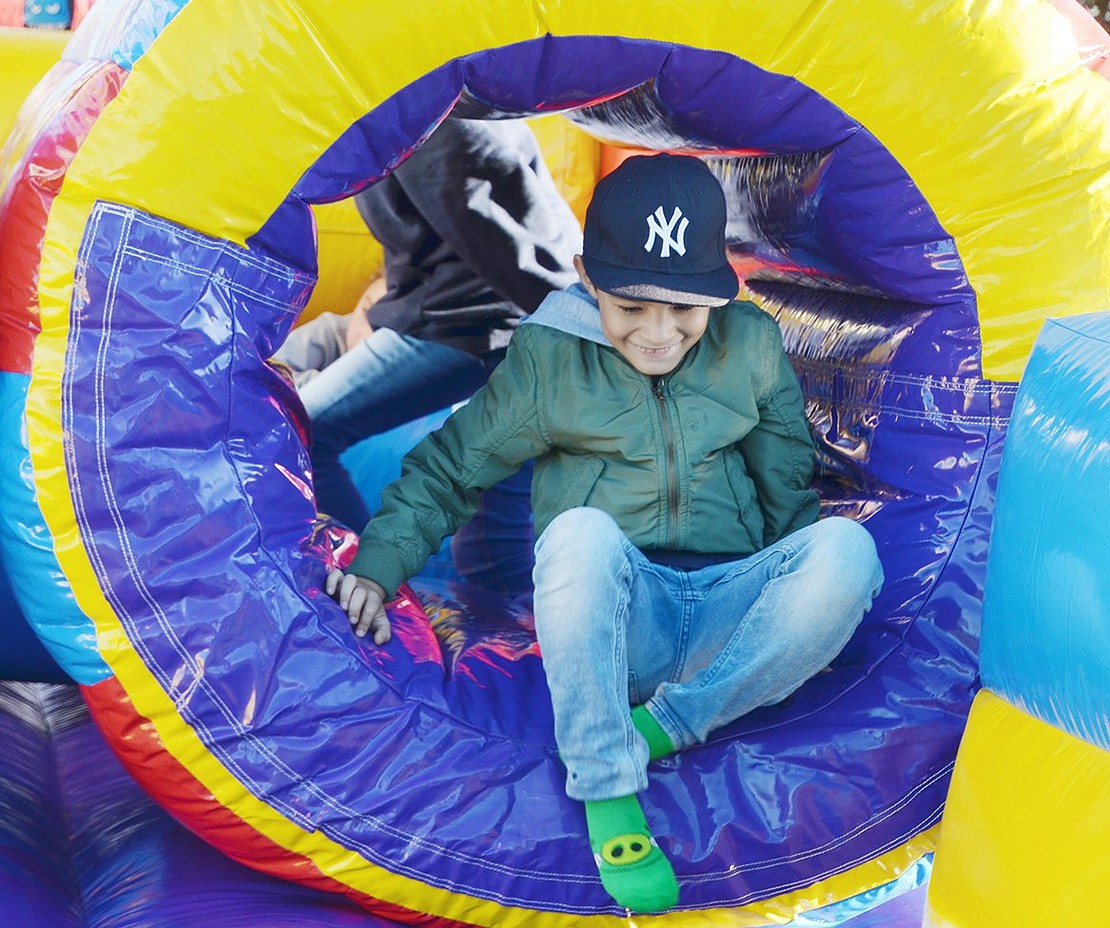 Oak Street resident and John F. Kennedy Elementary School second-grader Mauricio Bonilla is nothing but smiles as he climbs out of the bouncy house obstacle course to greet his sister.