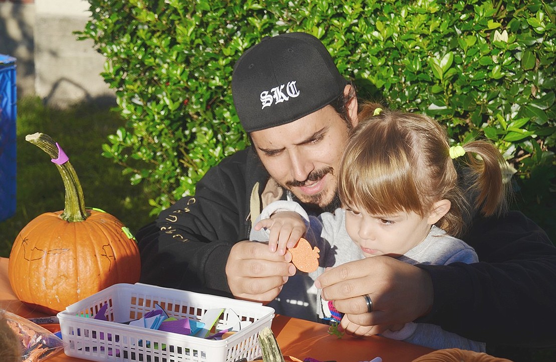 Richard Gasparino helps his 3-year-old daughter Abigail decorate a pumpkin. The duo walked down the block from their house on Park Avenue just to check out the festival. 