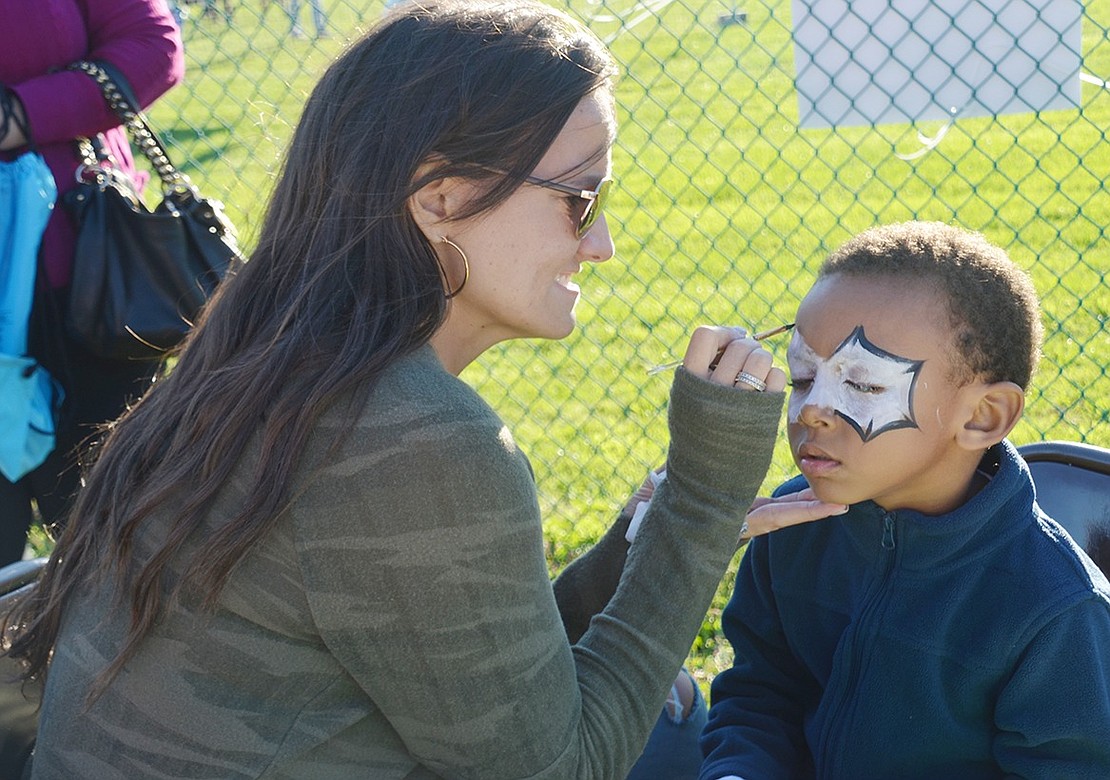 Stamford, Conn. kindergartener Christopher Pierce sits patiently still so Park Avenue School PTO Vice President Laura Luzzi can paint a spider web around his eyes.