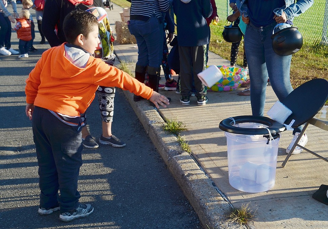 Park Avenue Elementary School second-grader Carlos Hernandéz throws a roll of toilet paper into a fake toilet for one of the many tossing games at the festival.